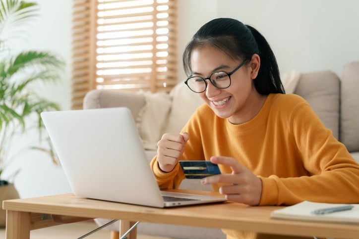 beautiful young woman are buying online with a credit card while sitting in the living room morning. Women are using a computer laptop and doing online transactions at home. | MemberPress